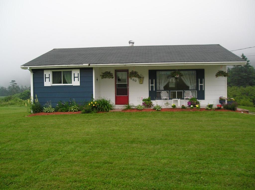 uma pequena casa com uma porta vermelha e um quintal em Gulliver's Cove Oceanview Cottages em Centreville