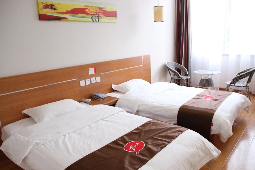 a hotel room with two beds with white sheets at Thank Inn Chain Hotel Shandong Qingdao Development Zone Lingzhushan in Qianwan