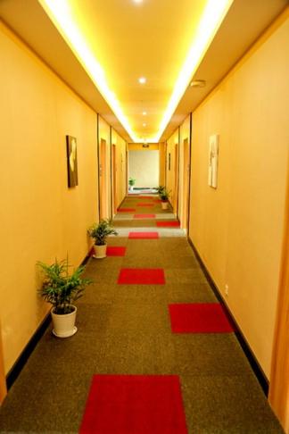 un largo pasillo con alfombras rojas en el suelo de un edificio en Thank Inn Chain Hotel Jiangsu Wuxi Binhu District Taihu Meiyuan en Wuxi