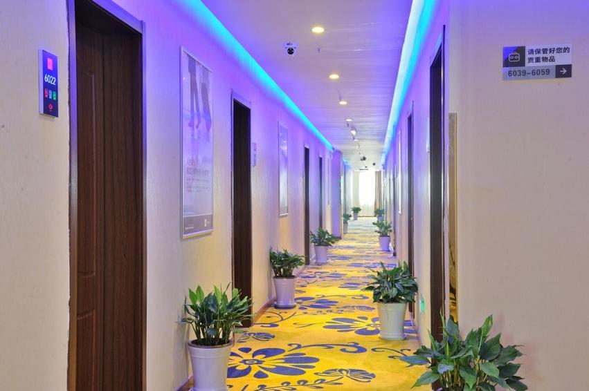 a hallway with potted plants on a yellow floor at JUNYI Hotel Jiangsu Suzhou Industrial Park Chefang Songze in Suzhou