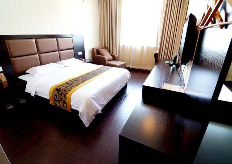 a hotel room with a large bed and a television at JUNYI Hotel Shaanxi Xi'an North 3rd Ring Daminggong Building Materials Market in Xi'an