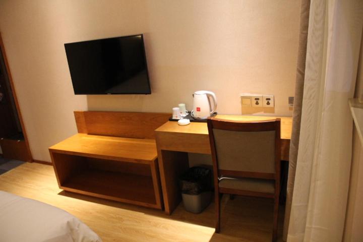 a hotel room with a desk with a television and a chair at Thank Inn Plus Hotel Fengxian Xidu in Xidu