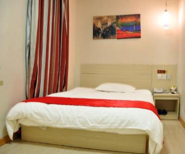 Schlafzimmer mit einem Bett mit einer roten und weißen Decke in der Unterkunft Thank Inn Chain Hotel Shandong Ningyang West Street in Ningyang