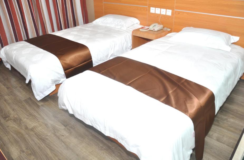 a hotel room with two beds and a phone in it at Thank Inn Chain Hotel Shandong Qingdao Junfeng Road in Qingdao