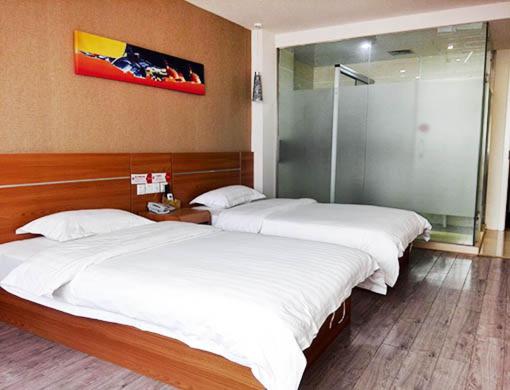 two twin beds in a room with a shower at Thank Inn Chain Hotel Hubei Wuhan Dongxihu District Jinghe Street in Wuhan