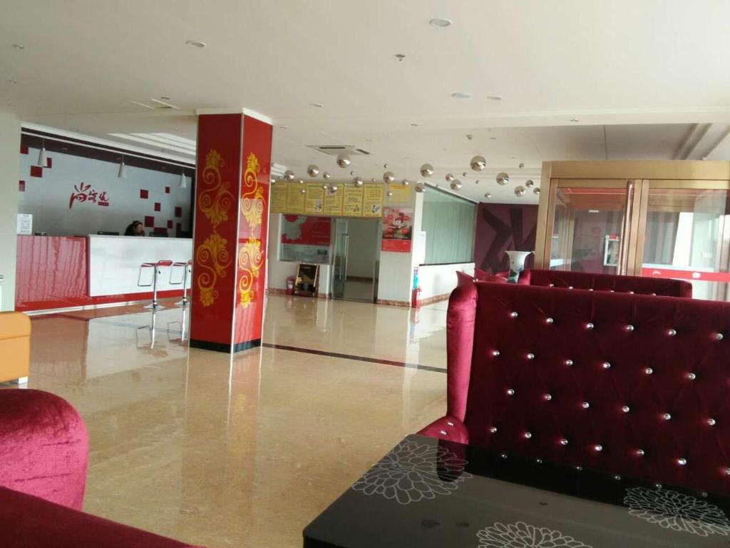 uma sala de estar com um sofá vermelho e uma cozinha em Thank Inn Chain Hotel Shanxi Lvliang Jiaokou County West Street em Xiazhuang
