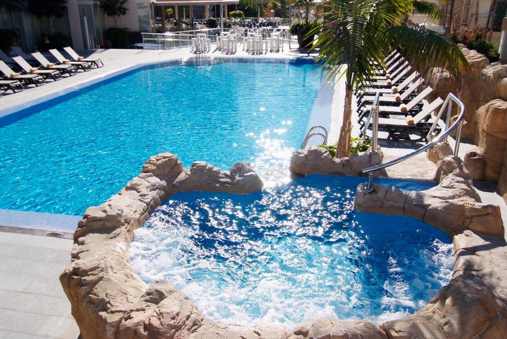 a swimming pool with a rock slide in a resort at Sandos Monaco - Adults Only in Benidorm