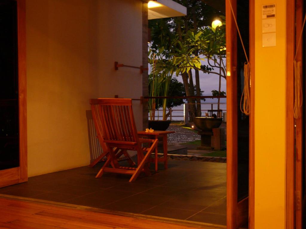 a wooden chair sitting on the porch of a house at JavaCove Beach Hotel in Batukaras