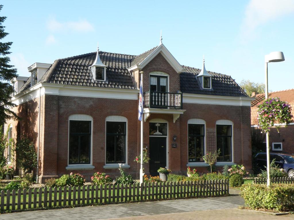 a red brick house with a fence in front of it at B & B Eindelinge in Serooskerke