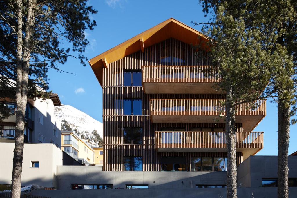 ein Gebäude mit einer Holzfassade mit Bäumen in der Unterkunft Alpine Lodge Chesa al Parc in Pontresina
