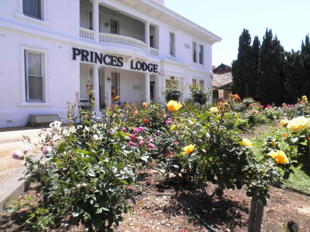 einem Blumengarten vor einem weißen Gebäude in der Unterkunft Princes Lodge Motel in Adelaide