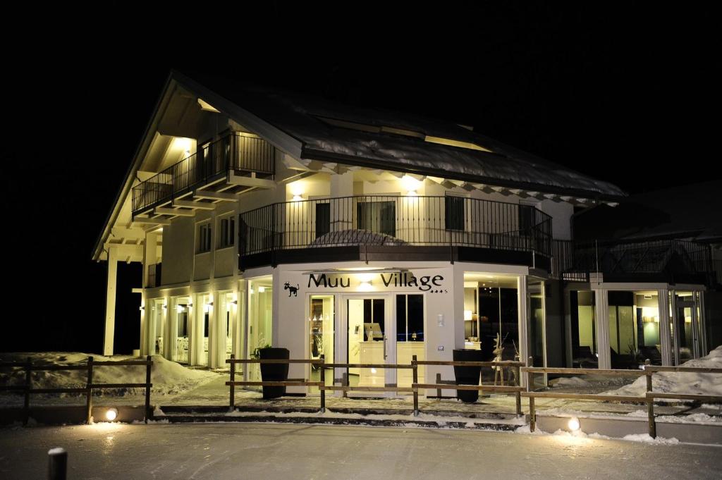 a large white building with a music village sign at night at Muu Village in Folgaria