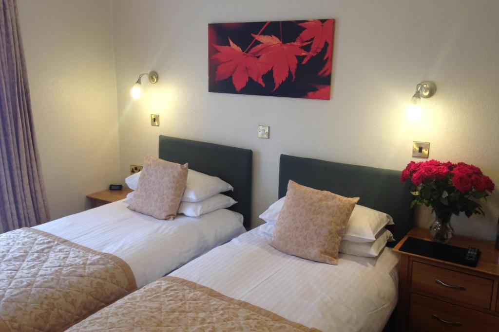 a hotel room with two beds and a vase of flowers at The Coach House in Melbourne