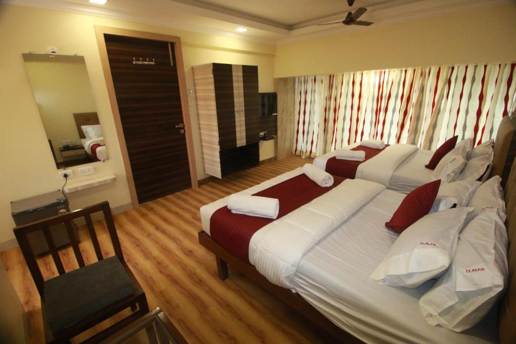 a hotel room with two beds and a mirror at Hotel Alfa International in Mumbai
