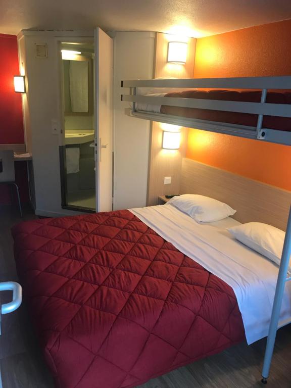 a bedroom with a bed with a red comforter at Premiere Classe Montbeliard - Sochaux in Sochaux