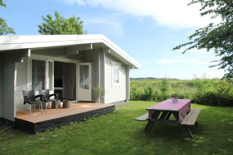 een klein huis met een terras en een tafel bij Cozy Cottage in Warmenhuizen