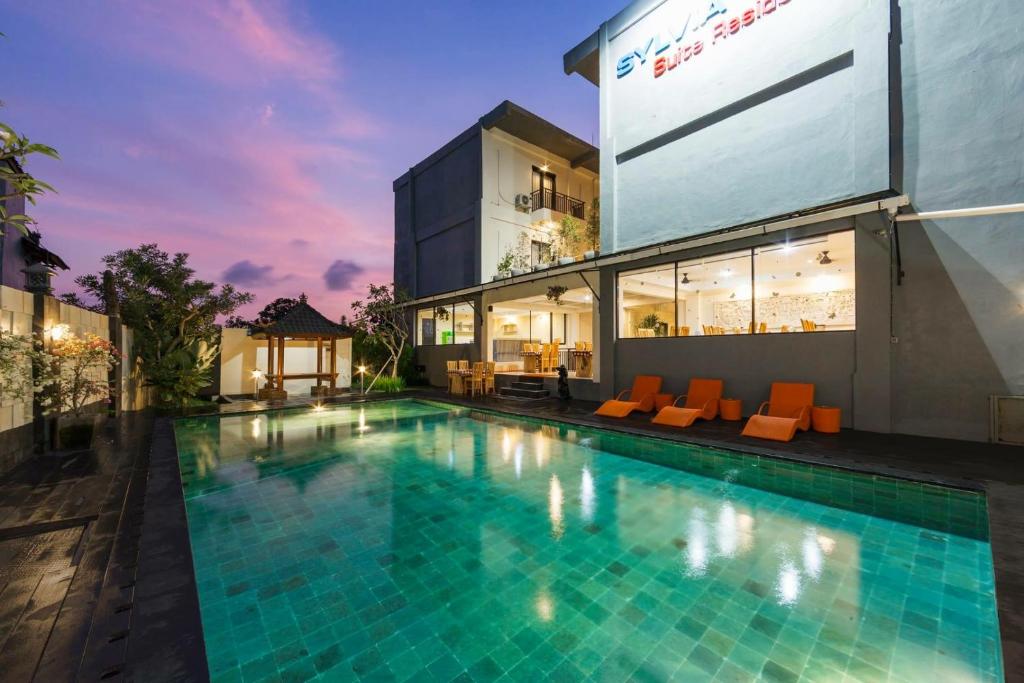 a swimming pool in front of a building at RedDoorz Plus near Mall Bali Galeria 2 in Denpasar