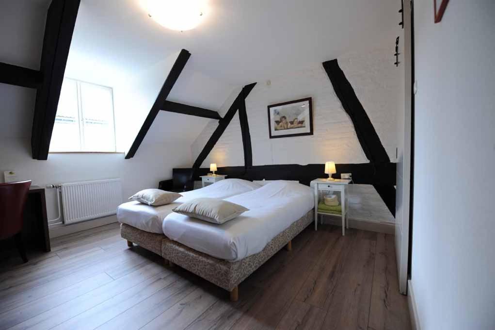 a bedroom with a large bed and a large window at Hotel De Oude Brouwerij in Mechelen