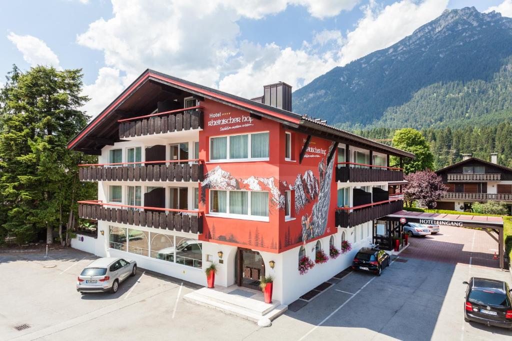 ein rotes Gebäude mit Autos auf einem Parkplatz in der Unterkunft Hotel Rheinischer Hof in Garmisch-Partenkirchen