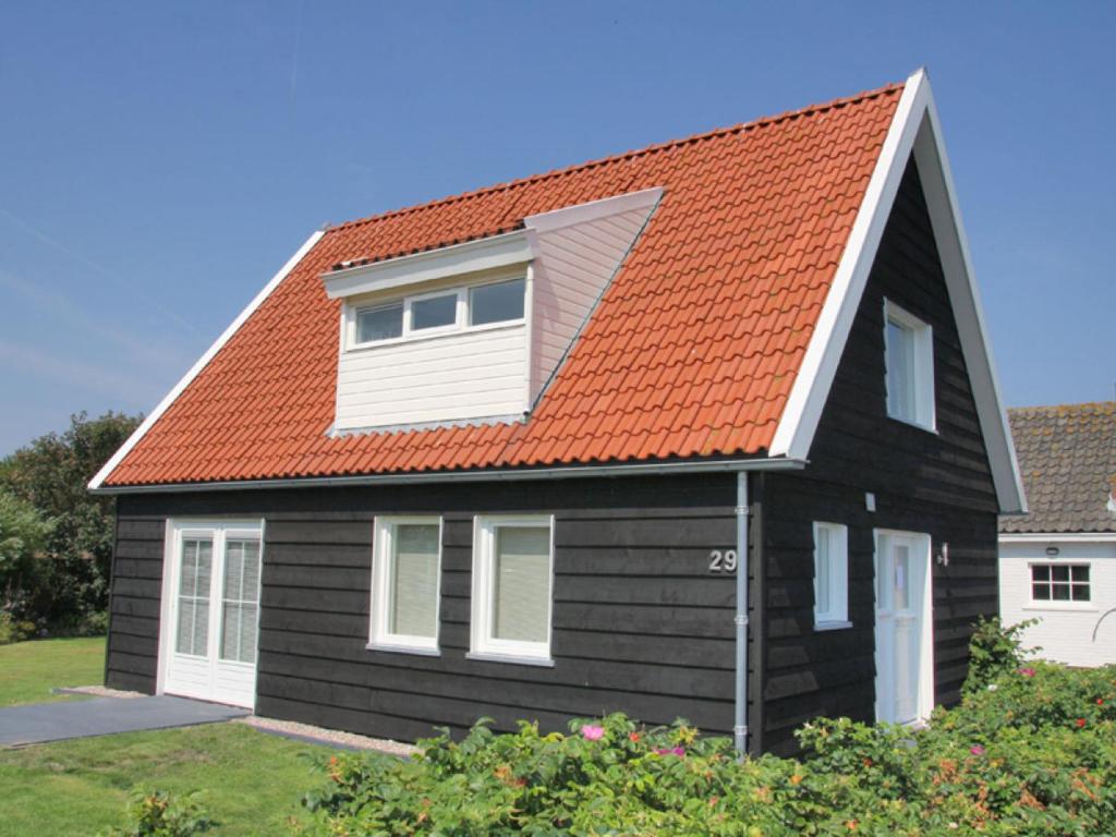ein orangefarbenes überdachtes Haus mit orangefarbenem Dach in der Unterkunft Strandvilla Roots in Callantsoog