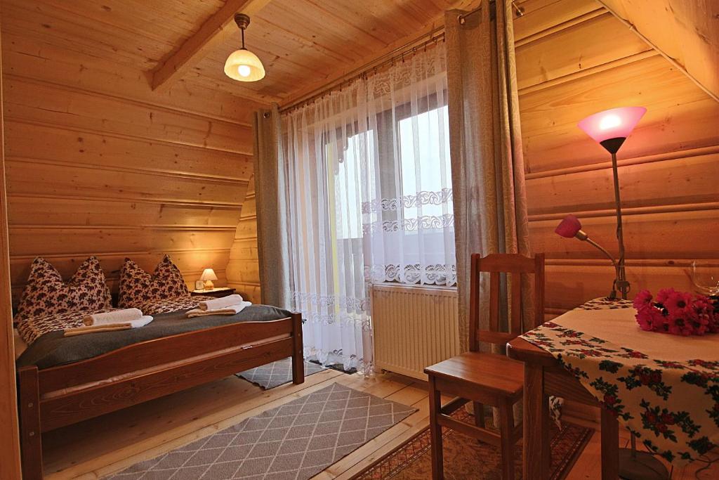 a bedroom with a bed and a table and a window at Noclegi Brzegi in Brzegi