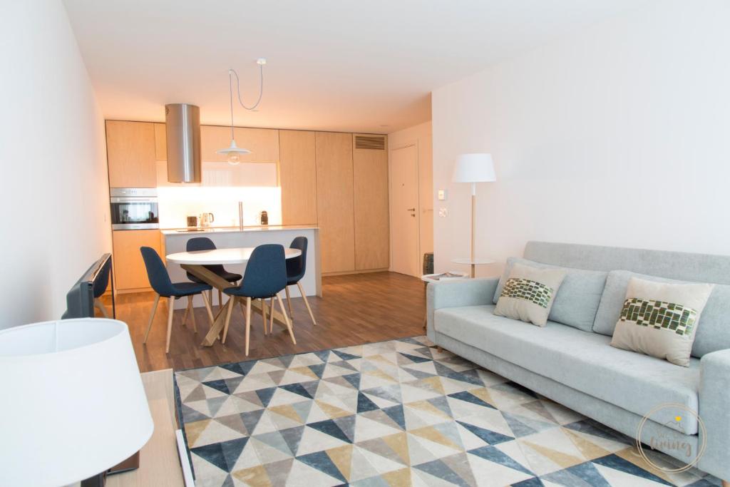ein Wohnzimmer und eine Küche mit einem Sofa und einem Tisch in der Unterkunft Oporto Ceuta Residences - Residence 6 by We Do Living in Porto