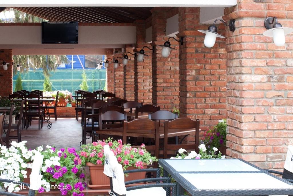 a patio with tables and chairs and a brick wall at Piazzetta Bacau in Bacău