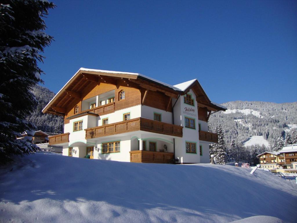 un edificio en la cima de una colina nevada en Holiday-Appartements, en Flachau