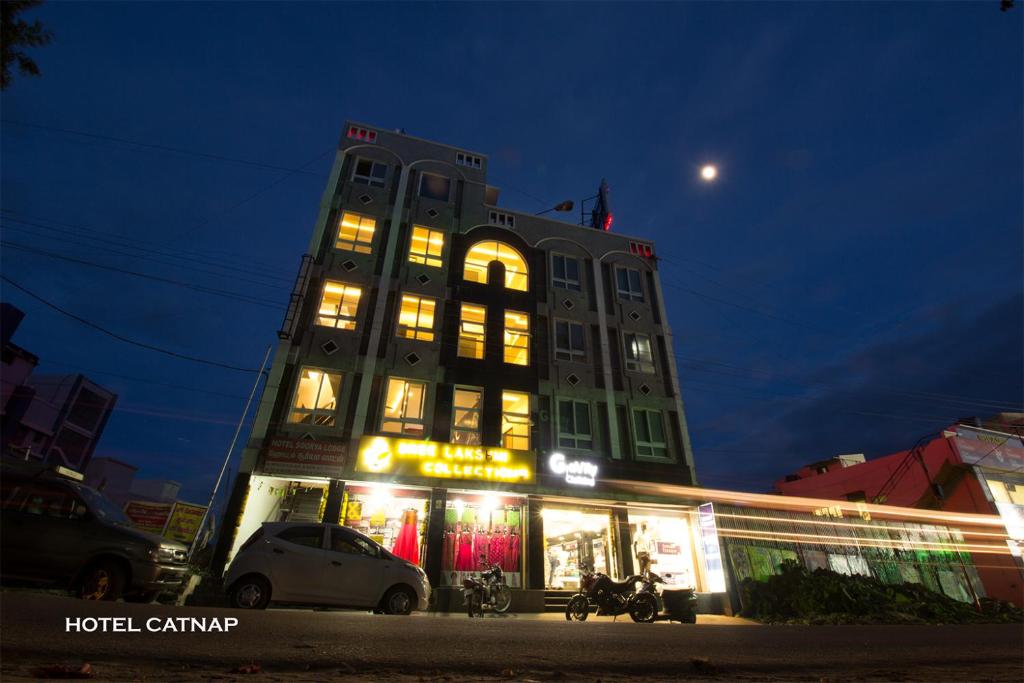 un edificio alto con luces encendidas por la noche en Hotel Catnap, en Mettuppālaiyam