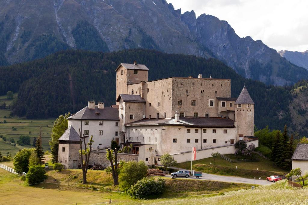 ein großes Schloss auf einem Hügel mit Bergen im Hintergrund in der Unterkunft Schloss Naudersberg in Nauders