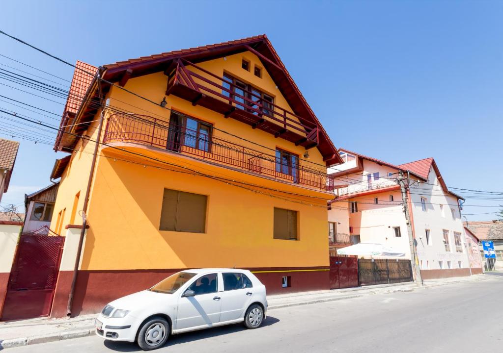 a small car parked in front of a yellow building at Pension La Viorel Isaila in Sibiu