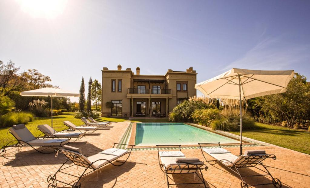 una casa con piscina con sedie e ombrellone di Villa de Luxe avec Piscine Privée et Golf a Marrakech