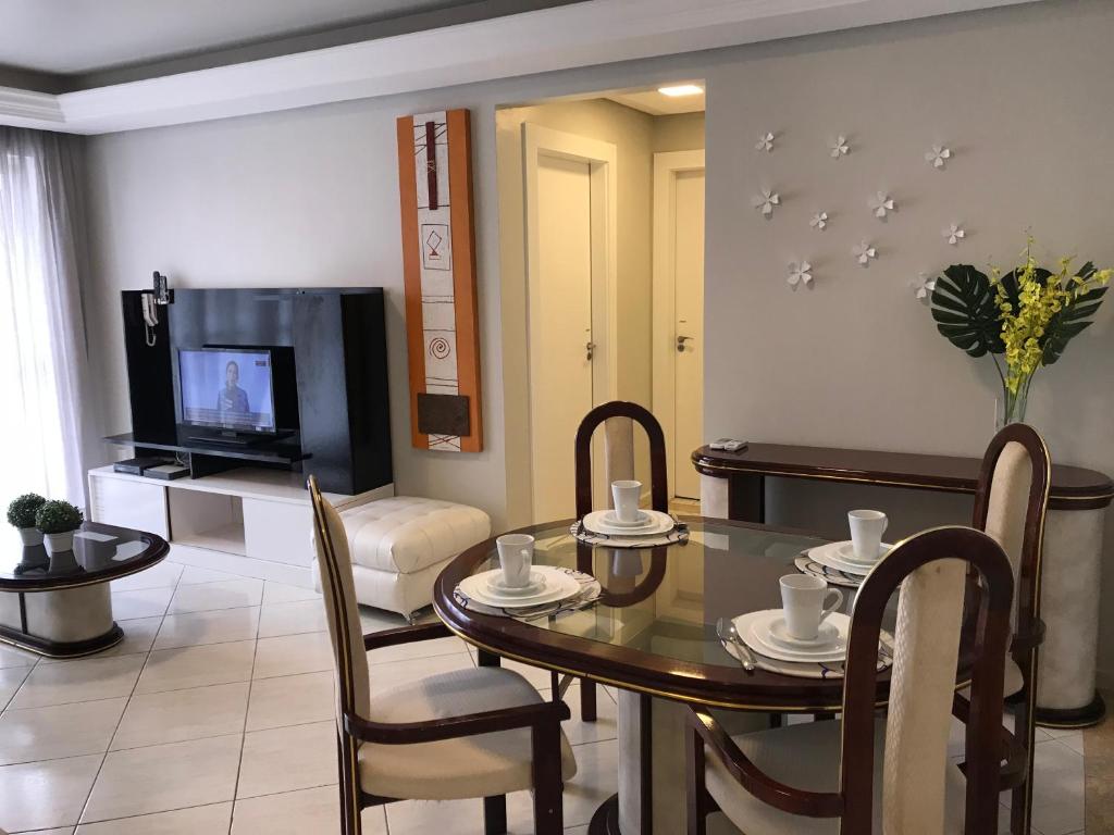 a living room with a dining room table and a television at Apartamento Central 2 Quartos in Balneário Camboriú