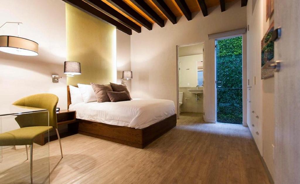 1 dormitorio con 1 cama y 1 mesa con silla en Othelo Boutique Hotel Mexico, en León