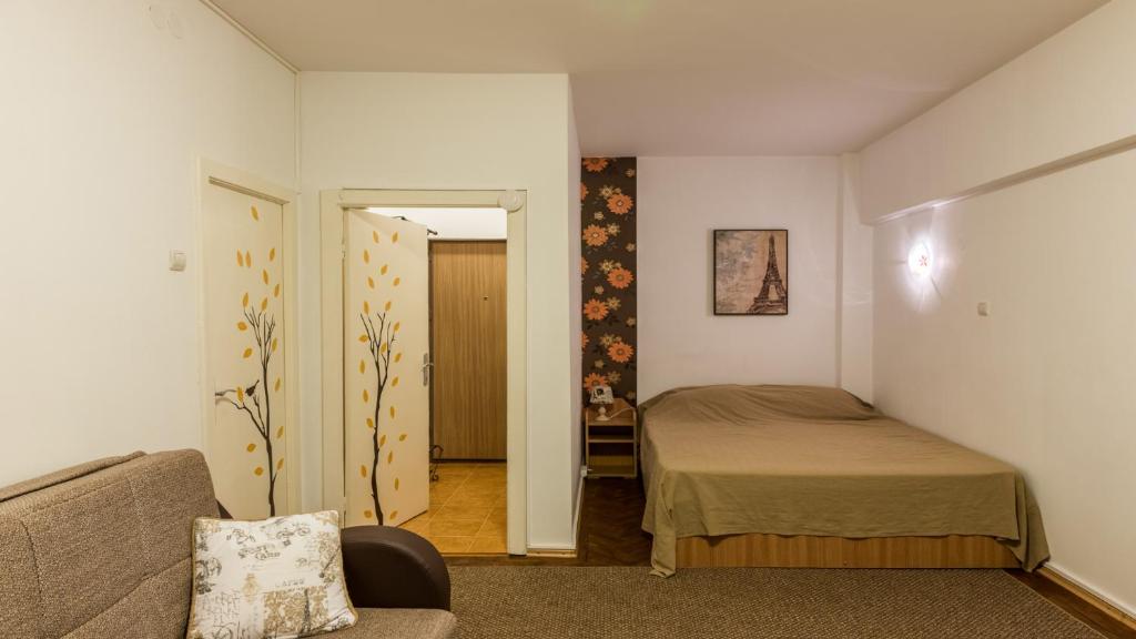 um pequeno quarto com uma cama e um sofá em Inner Circle Studio em Bucareste