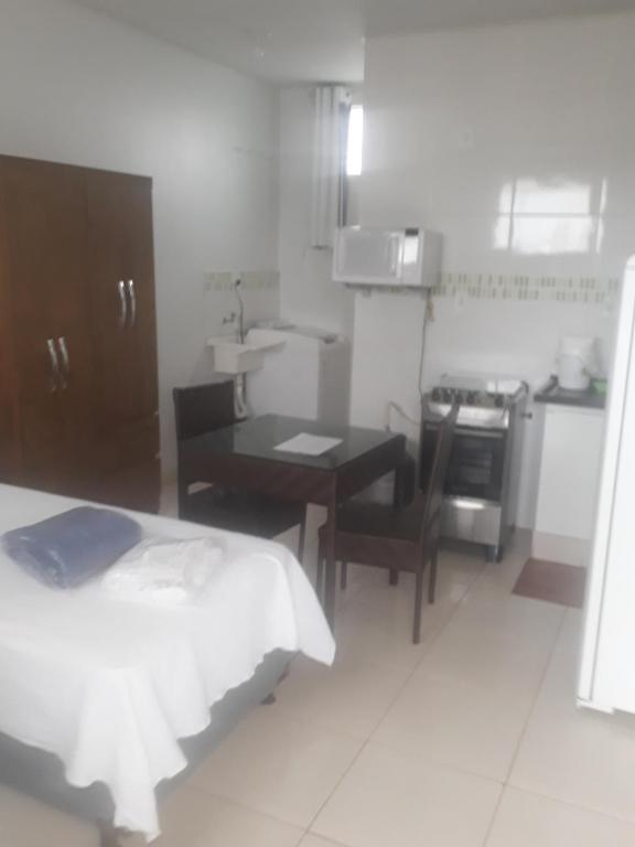 um quarto com uma cozinha, uma mesa e uma sala de jantar em Flat Econômico Uberlândia em Uberlândia