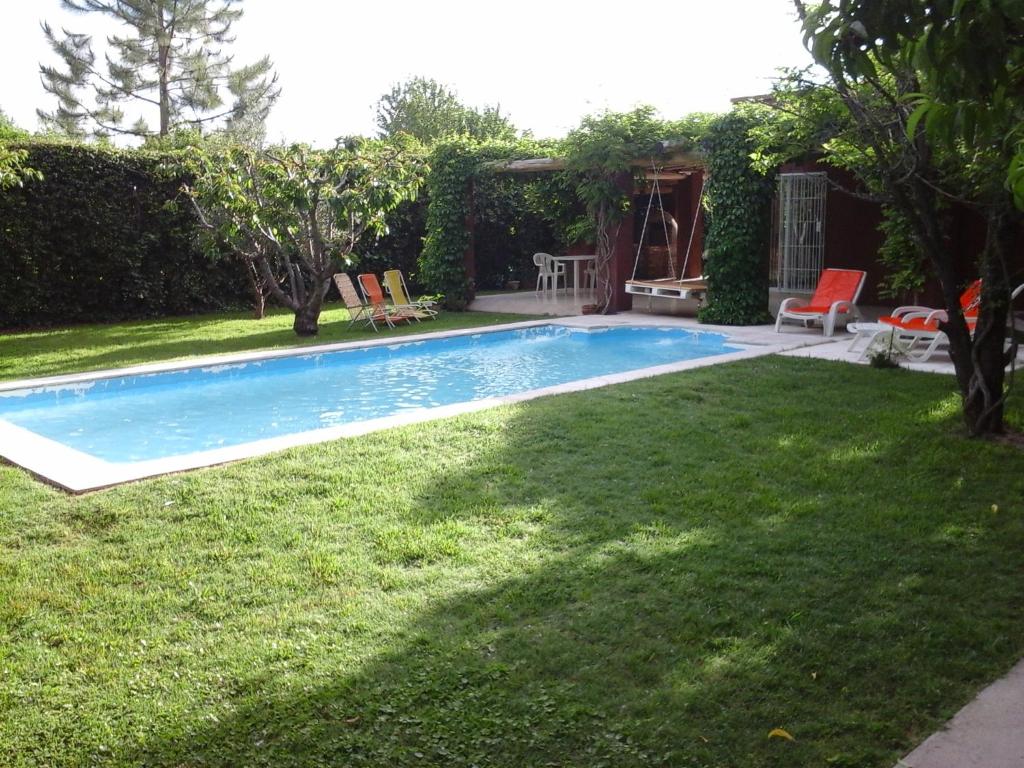 ein Swimmingpool in einem Hof mit grünem Gras in der Unterkunft Casa en la Ruta del Vino in Mendoza
