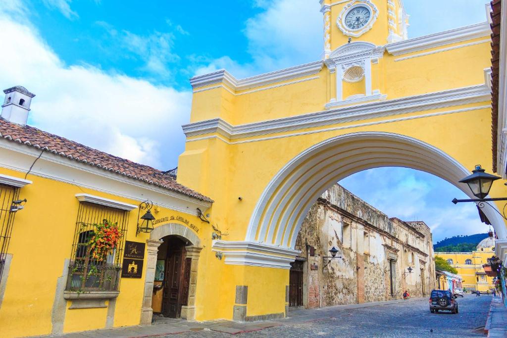 a yellow building with a clock tower on a street at Hotel Convento Santa Catalina by AHS in Antigua Guatemala