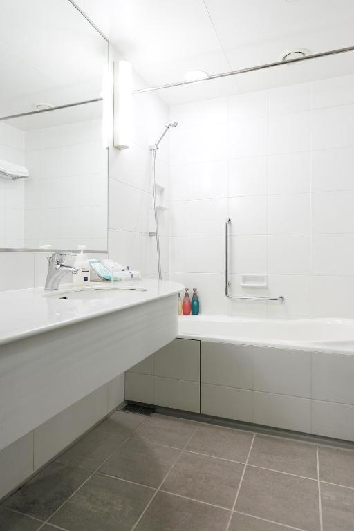 a white bathroom with a sink and a tub at Haneda Excel Hotel Tokyu Haneda Airport Terminal 2 in Tokyo