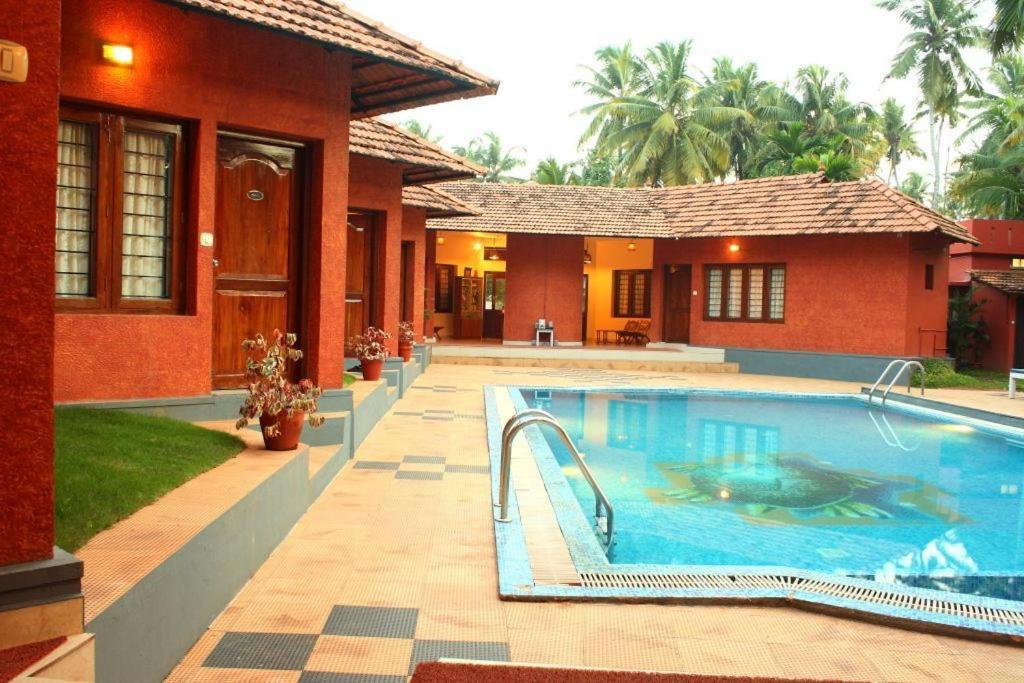 a house with a swimming pool in front of a house at Deshadan Cliff & Beach Resort,Varkala in Varkala