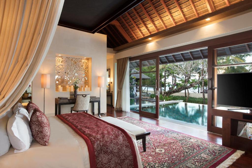 a bedroom with a bed and a television and a pool at The Royal Santrian in Nusa Dua