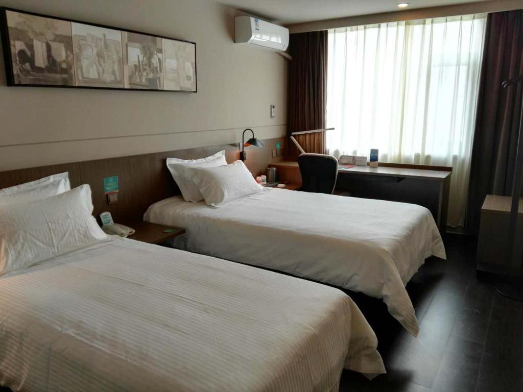 a hotel room with two beds and a desk at Jinjiang Inn Select Shaoxing Jiefang North Road in Shaoxing