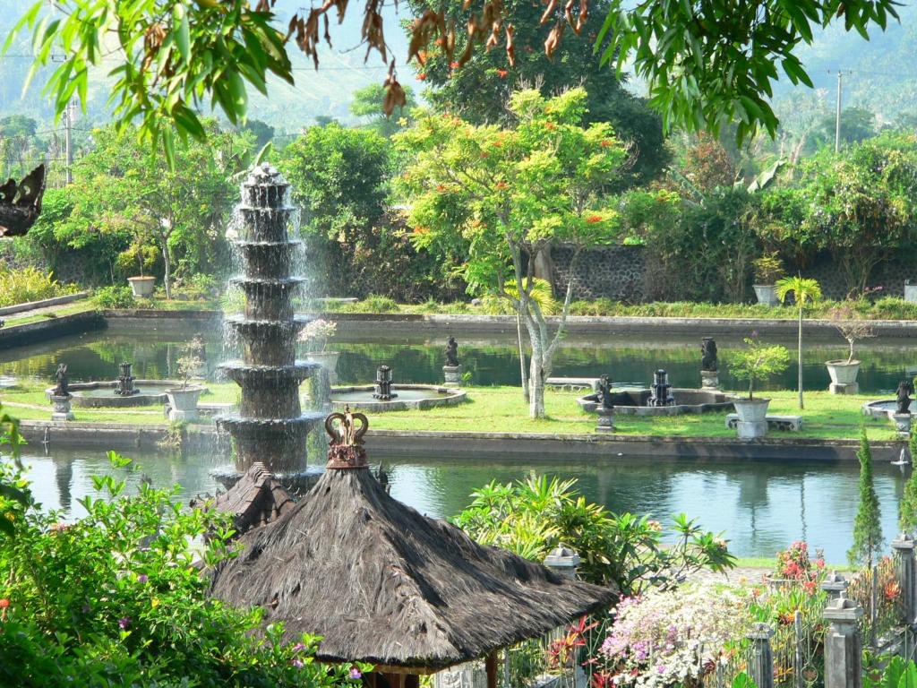 a fountain in the middle of a pond in a park at Tirtagangga Water Palace Villas in Tirtagangga