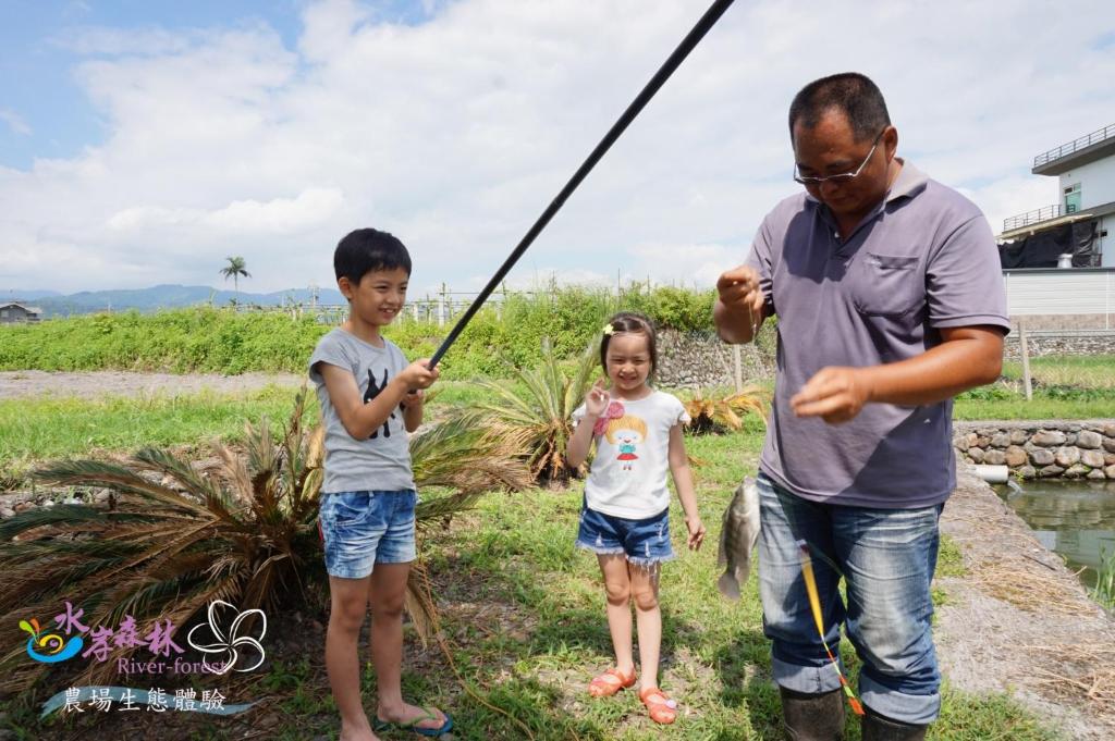 a man and two children with a fishing pole at River Forest Leisure Farm in Dongshan