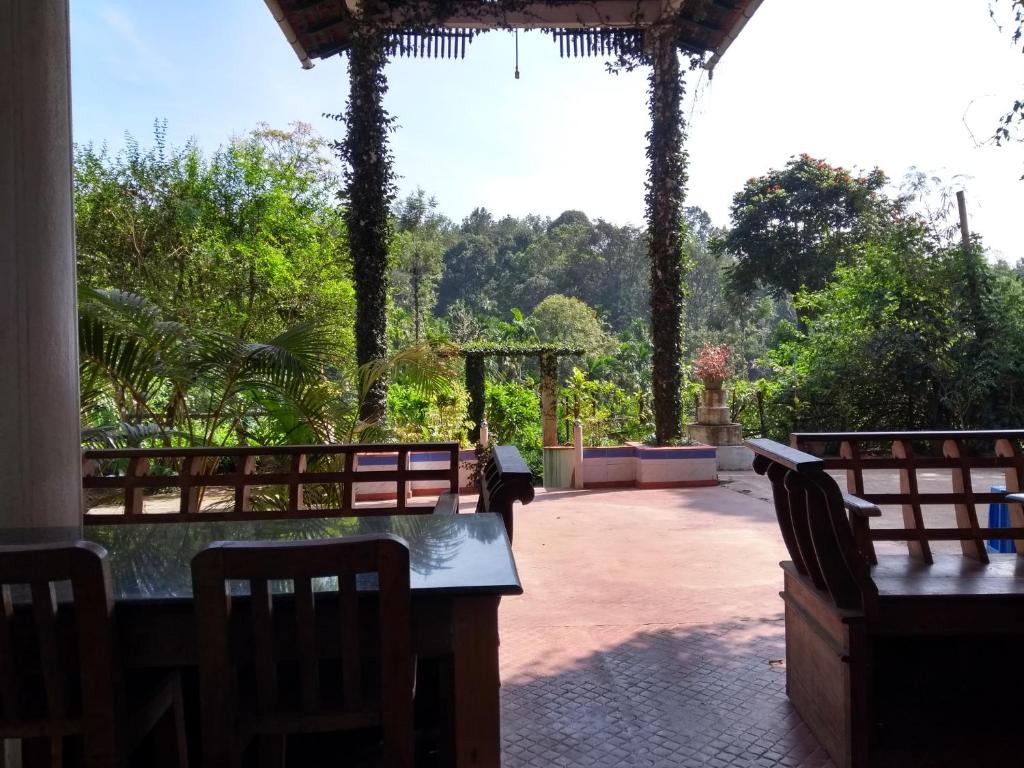 eine Terrasse mit einem Tisch, Stühlen und Bäumen in der Unterkunft Coorg 4 C's Little Paradise in Madikeri