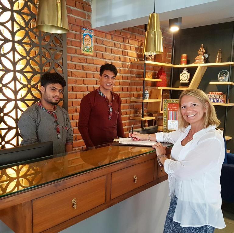 a woman standing in front of a counter with two men at Utse Suites in Bangalore