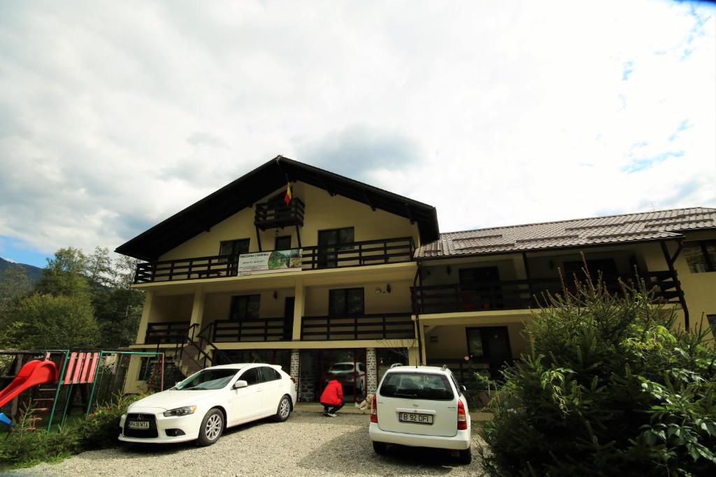 two white cars parked in front of a building at Pensiunea Ciobanelu in Malaia