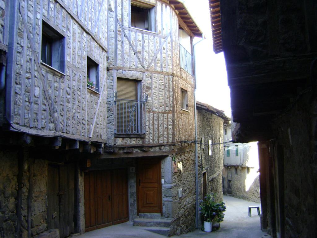 un callejón con edificios de piedra antiguos y una puerta de madera en Casa Lopez, en San Martín del Castañar