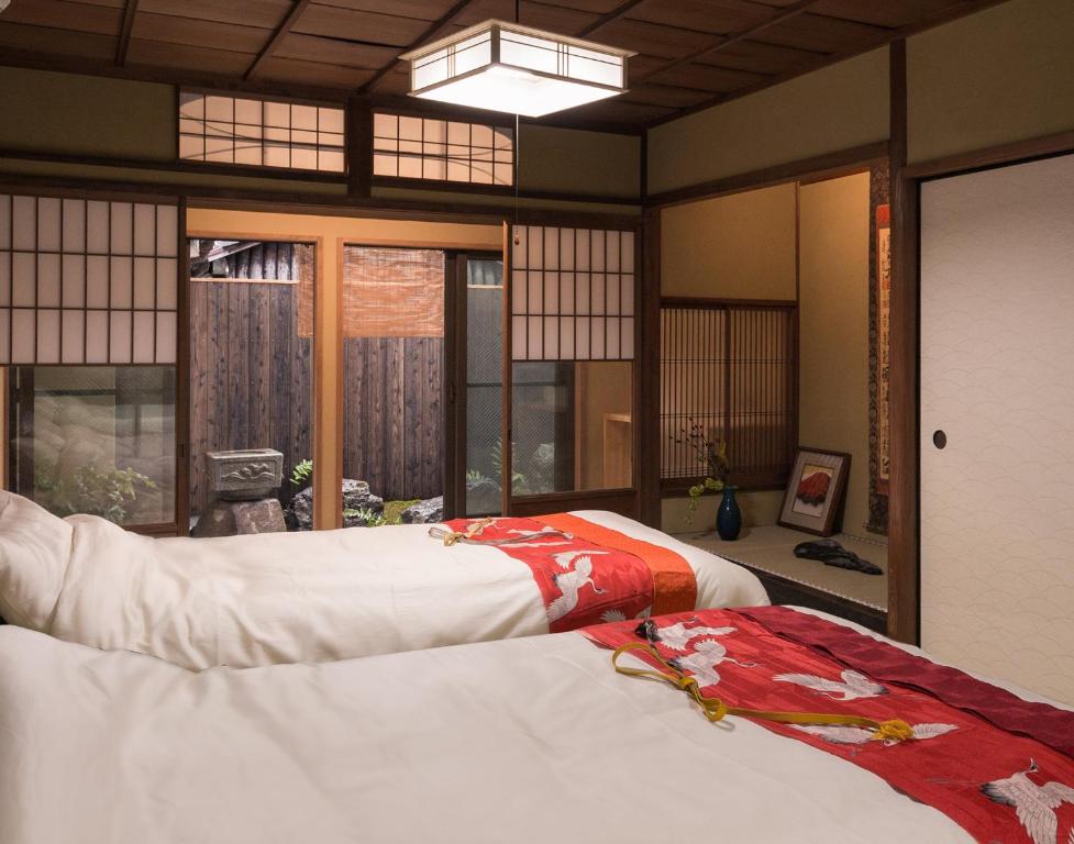 two beds in a room with windows at Marikoji Inn Kyoto in Kyoto
