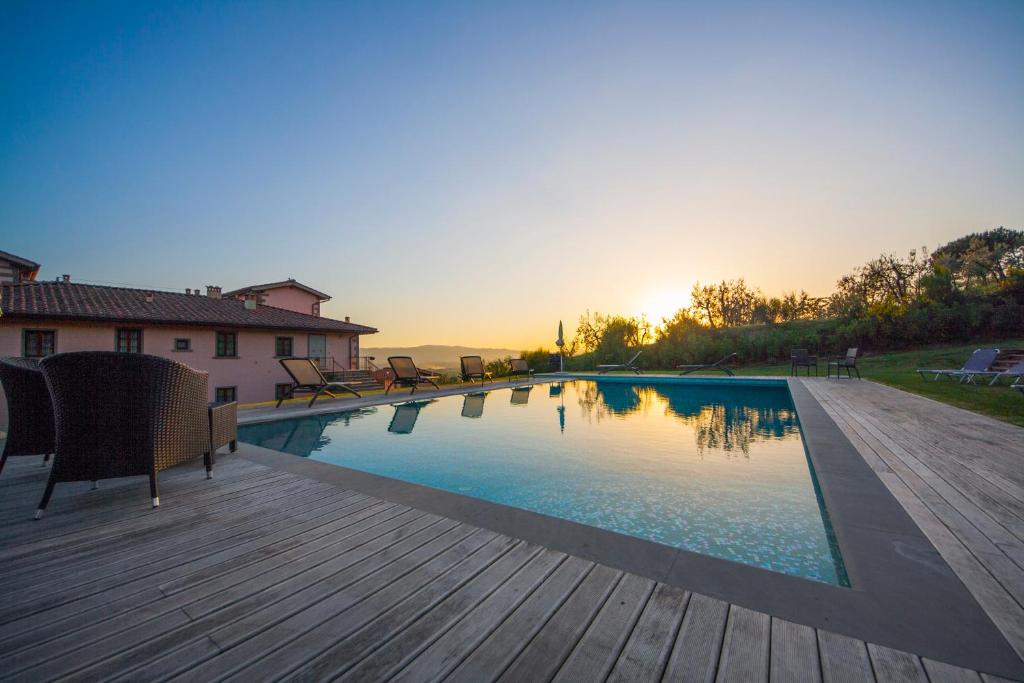 a swimming pool with a wooden deck and the sunset at Casaforte Villa & Resort in Loro Ciuffenna